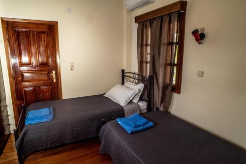 two beds in a room with a door and a window at Villa Kontos in Kamena Vourla