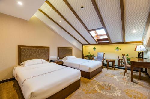 a bedroom with two beds and a desk and a table at S&N Hotel Sanqingshan in Shangrao