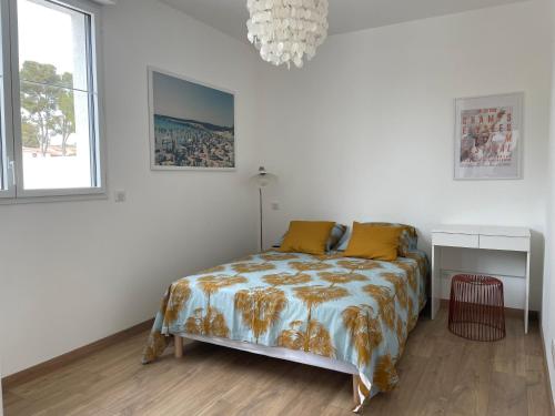 Habitación blanca con cama y lámpara de araña. en Appartement T2 piscine et plage en Carry-le-Rouet