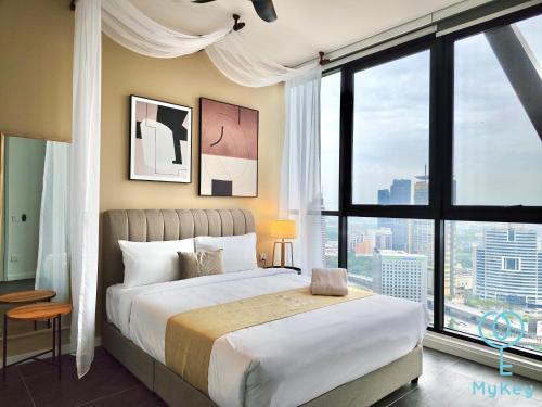 ein Schlafzimmer mit einem großen Bett und großen Fenstern in der Unterkunft Scarletz Suites KLCC by Mykey Global in Kuala Lumpur
