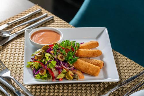 a plate of food with a salad and dipping sauce at Clove Villa in Kandy