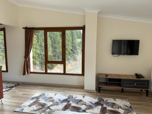uma sala de estar com uma televisão de ecrã plano na parede em MEŞEİÇİ BUTiK HOTEL em Macka