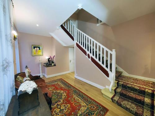 a living room with a staircase and a rug at Logis Vélès in Aubin