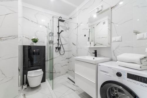een witte badkamer met een wasmachine en een wastafel bij Apartament Baltic Sun in Sztutowo