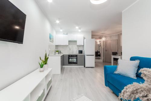 een woonkamer met een blauwe bank en een keuken bij Apartament Baltic Sun in Sztutowo