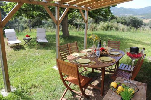 une table et des chaises en bois sous une pergola dans l'établissement Maquis et plage, à Sollacaro