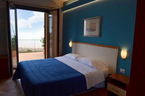 1 dormitorio con 1 cama con pared azul en L'Infinito Agriturismo - Rooms & Breakfast en SantʼAlfio