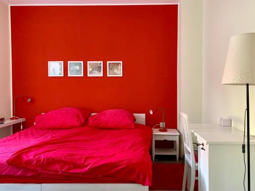 1 dormitorio rojo con 1 cama con pared roja en die Senfbude - schöne, ebenerdige 2-Raum-Apartments mit Stellplatz und Terrasse, en Leipzig