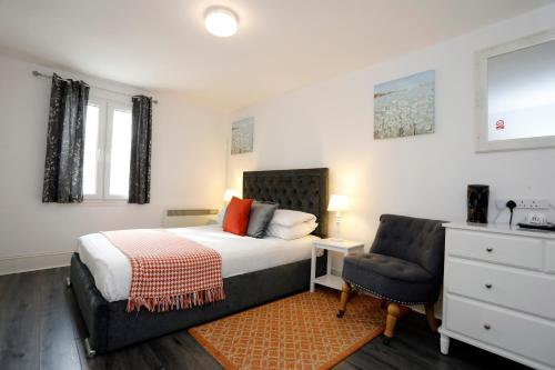 a bedroom with a bed and a chair at Bexley Village Hotel in Bexley