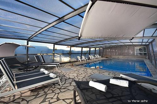 a swimming pool with chairs and a large roof at סוויטות כחול לבן - בקתות וסוויטות מושלמות עם ג'קוזי פרטי ובריכה מחוממת במתחם in Shahar