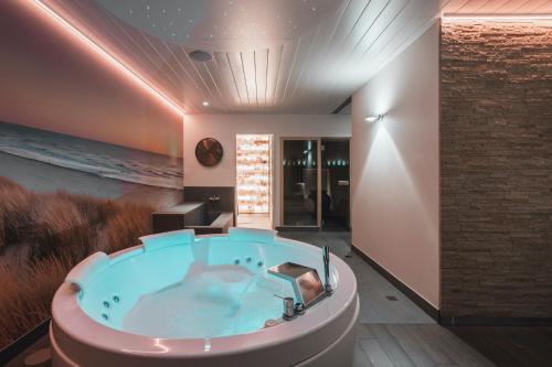 a jacuzzi tub in a room with a ocean at Boutique Hotel 'Hof ter Duinen' in Oostduinkerke