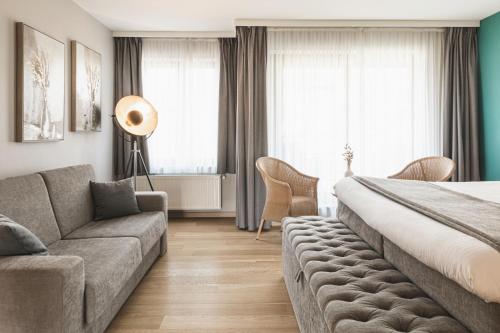 une chambre d'hôtel avec un lit et un canapé dans l'établissement Boutique Hotel 'Hof ter Duinen', à Oostduinkerke