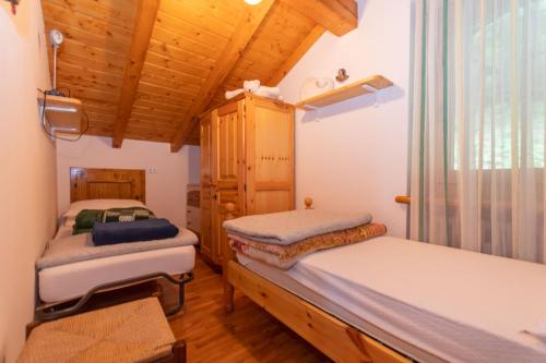 two beds in a room with wooden ceilings at Casa Fagher in Canale dʼAgordo