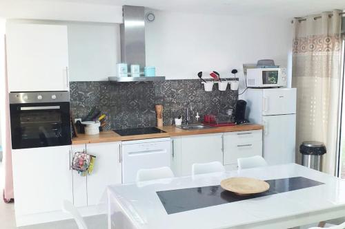 une cuisine avec des placards blancs et un comptoir blanc dans l'établissement Villa la Murenne, à Argelès-sur-Mer