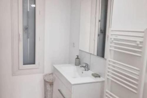 une salle de bain blanche avec un lavabo et un miroir dans l'établissement Villa la Murenne, à Argelès-sur-Mer