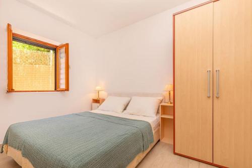1 dormitorio con 1 cama, armario y ventana en Family Apartment close to the Beach en Mlini
