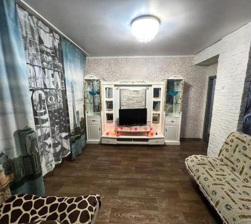 - un salon avec une télévision et un canapé dans l'établissement Квартира, à Öskemen