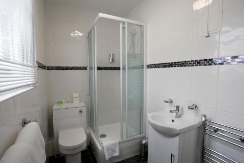 a bathroom with a shower and a toilet and a sink at Bexley Village Hotel in Bexley