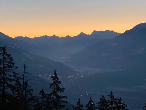 a view of a mountain range at sunset at Colorado Riders Chalet in Crans-Montana