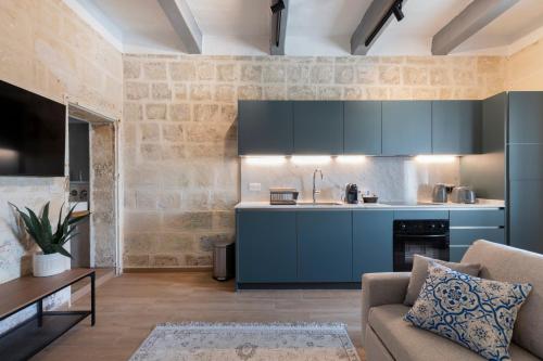 a kitchen with blue cabinets and a couch in a living room at Valletta Collection - Felix Apartments in Valletta