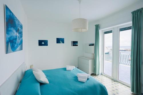 a bedroom with a blue bed and a large window at Capri holiday home with a sea view in Capri