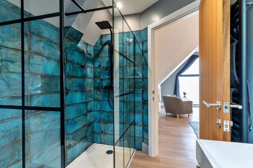 a glass shower in a bathroom with blue tiles at Finest Retreats - Blue Seas in Mousehole