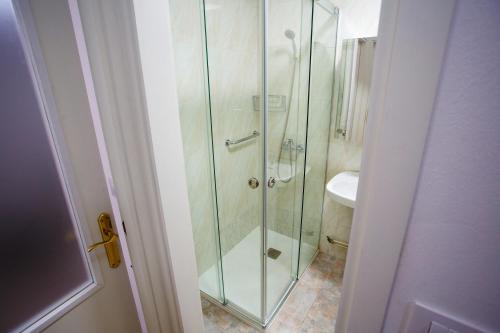uma cabina de duche em vidro na casa de banho com um lavatório em A Casiña de Juan em Corcubión