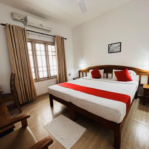 a bedroom with a large bed with red pillows at Pepper Route, Fort Kochi in Fort Kochi