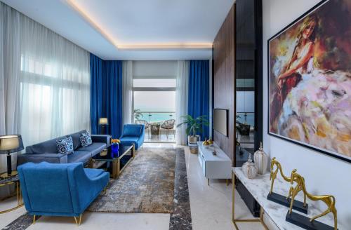 a living room with blue furniture and a large painting at Tolip Resort El Galala Hills in Ain Sokhna