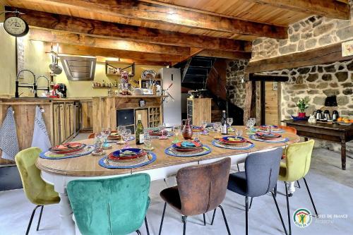 une cuisine avec une grande table entourée de chaises dans l'établissement Le Cocon du Vivarais, à Rochepaule