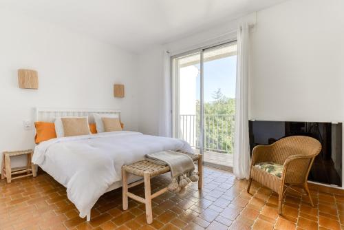 a white bedroom with a bed and a large window at Villa Cavi - Olivier in Le Grau-dʼAgde