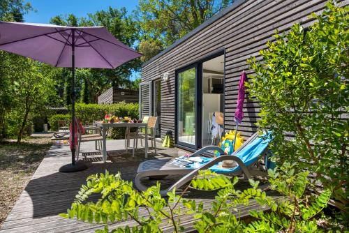 a patio with an umbrella and a table and chairs at Camping-Village Vacances Les deux Étangs in Seignosse