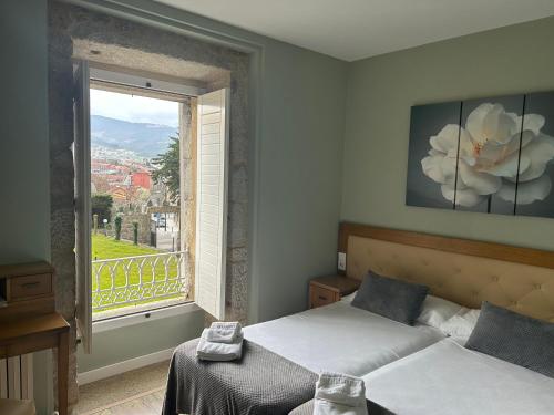 a bedroom with two beds and a large window at Pazo Pias P in Ramallosa