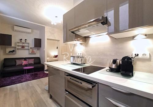 - une cuisine avec une cuisinière et un canapé dans la chambre dans l'établissement Viva Riviera Calm and Modern 1 Bedroom City Centre Cannes, à Cannes