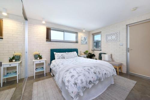 a bedroom with a large bed and two windows at Sandon Point Coastal Abode in Bulli