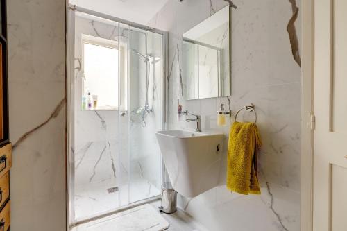 ein weißes Bad mit einem Waschbecken und einer Dusche in der Unterkunft Stylish Apartment steps from the Capital in Floriana
