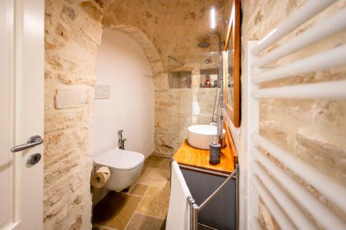 a bathroom with a white toilet and a sink at Esclusive luxury private trulli in Martina Franca