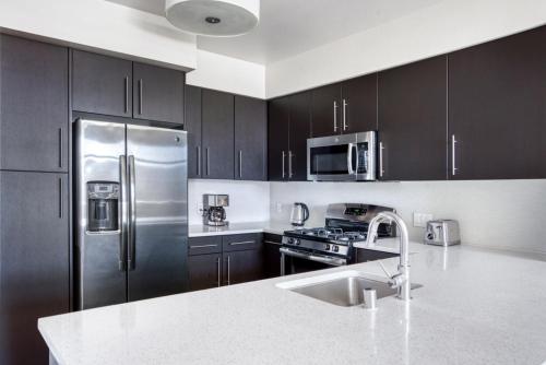 a kitchen with black cabinets and a stainless steel refrigerator at Redwood City 2BR w AC Gym WD nr Caltrain SFO-1110 in Redwood City