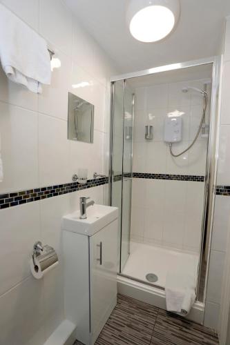 a white bathroom with a shower and a sink at Bexley Village Hotel in Bexley