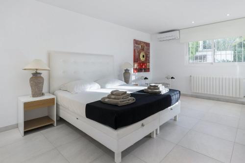 Un dormitorio blanco con una cama con toallas. en Begonia - Can Furnet, en Can Furnet