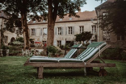 un banc assis dans l'herbe devant un bâtiment dans l'établissement La Fontaine Racine - Chambres d'hôtes, à La Ferté-Milon