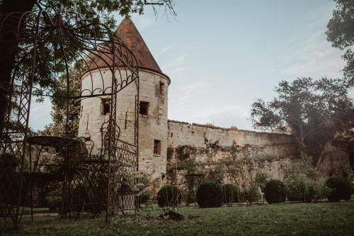 een oud stenen gebouw met een muur en bomen bij La Fontaine Racine - Chambres d'hôtes in La Ferté-Milon