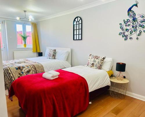 1 dormitorio con 2 camas y manta roja en Cheerful 3 Bedroom 2 Bathroom Bungalow by CozyNest, en Earley