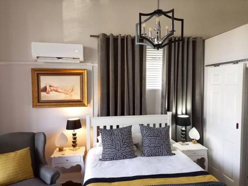 1 dormitorio con cama y lámpara de araña en La Damon 2 en Paarl