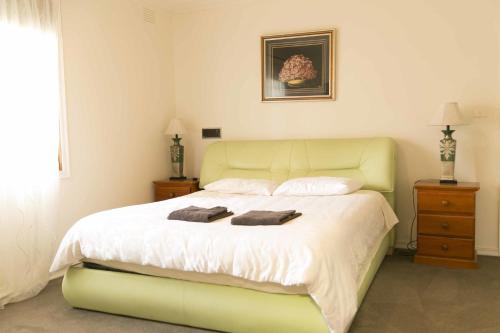 1 dormitorio con 1 cama verde y 2 toallas en Hawthorn Holiday House, en Melbourne