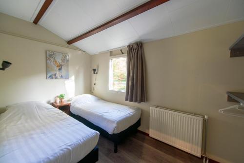 a bedroom with two beds and a window at Vakantiepark Westerbergen in Echten