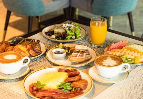 a table topped with plates of food and cups of coffee at Admiral Hotel Manila - MGallery Collection in Manila