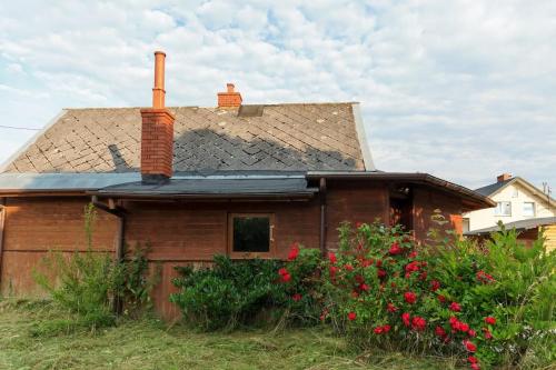 an old house with red flowers in front of it at Free Bikes, WiFi, AC, Garden, 2 Beds in Duczki