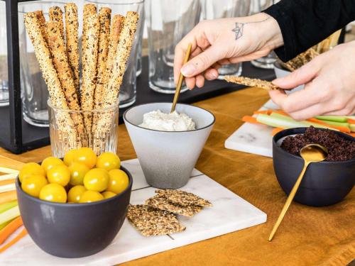 a person is preparing food on a table with snacks at Hôtel Mercure Paris Suresnes Longchamp in Suresnes