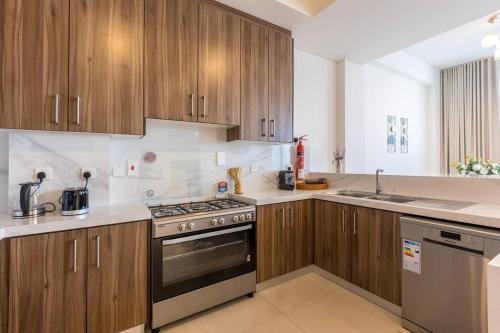 a kitchen with wooden cabinets and a stove top oven at Dream holiday home+private pool in Ras al Khaimah